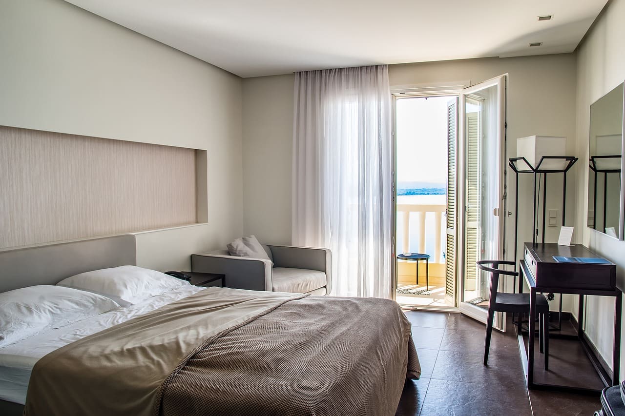 A bedroom with a bed, chair and balcony.