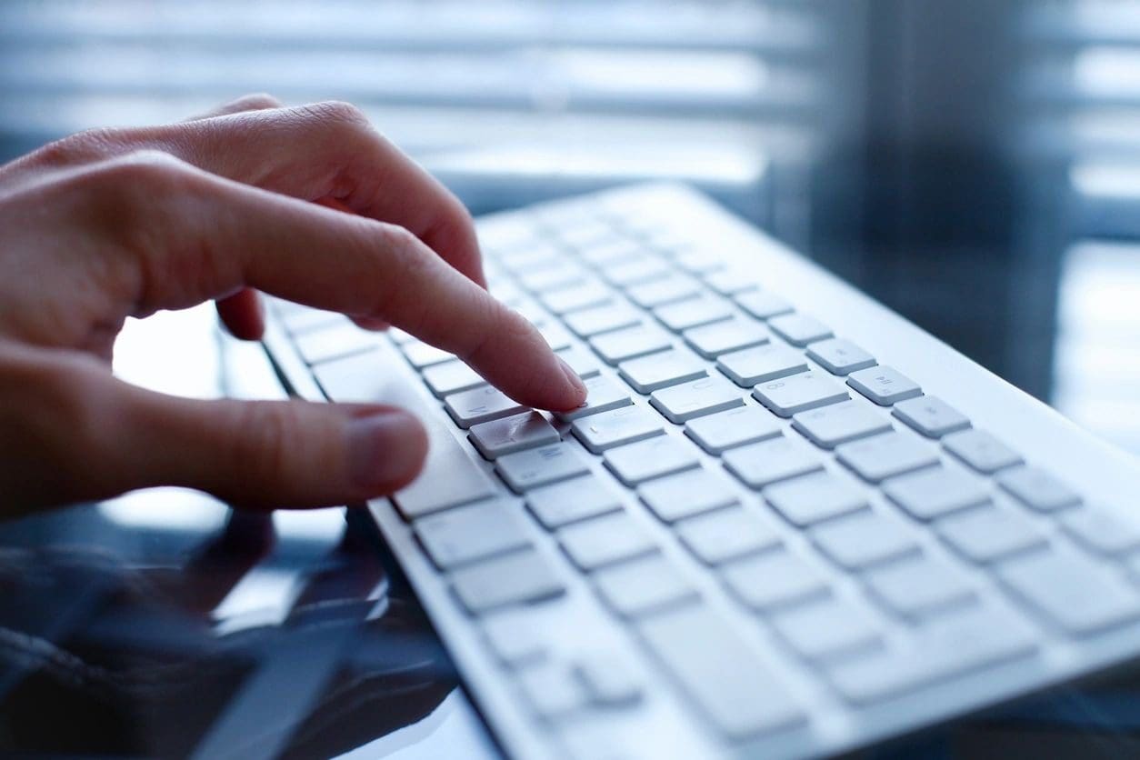 A person typing on a keyboard with their fingers.